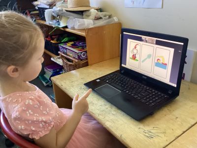 child at computer pointing to images on screen