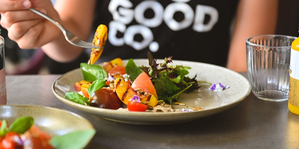 Plate of fresh salad with vegetables and leafy greens on a café table.